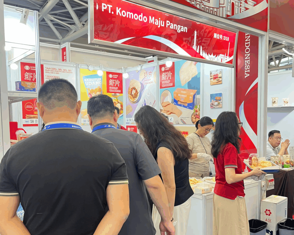 Komodo Foods booth at CISMEF 2025 in Guangzhou, featuring shrimp crackers, fish snacks, and traditional Indonesian condiments, with visitors sampling products and engaging with the team.